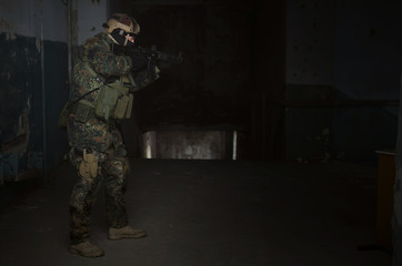 Fototapeta premium A army soldier takes aim with a rifle in his hands. Storming the building concept.