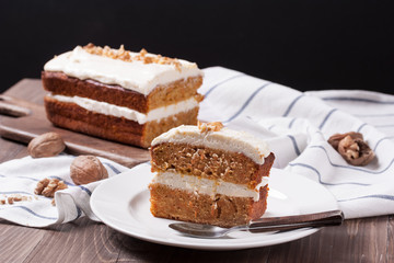 carrot cake with walnuts, on a dark wood background.