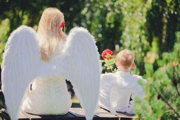 Beautiful mother and her toddler son wearing angel costumes. Cheerful moment, loving family.