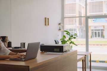 Closeup image of woman's hands using and typing on laptop keyboard on wooden table in office