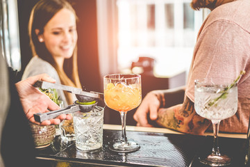 Happy friends drinking cocktails in trendy bar with professional bartender serving them
