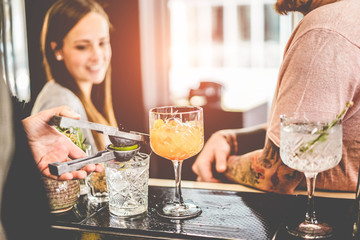 Happy friends drinking cocktails in trendy bar with professional bartender serving them