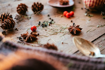 Details of still life in the living room home interior. Beautiful cup of tea with spices and sweaters on a wooden background. Cozy autumn-winter concept