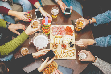 Top view of young people drinking beers and using smartphones at pub restaurant