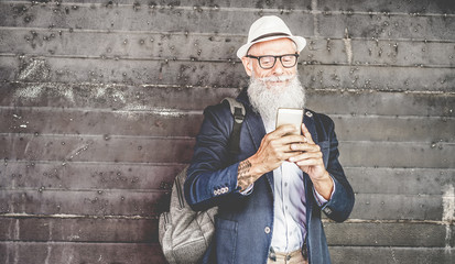 Trendy senior man using smartphone app with rusty metal background