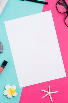 White A4 blank frame on a colorful pink and blue background with womens accessories,
