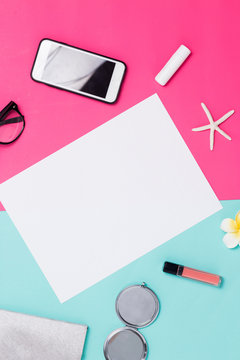 Beautiful white paper frame on colored background with smartphone, mirror, lipstick and glitter