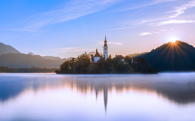 Lake Bled Slovenia at sunrise.  Beautiful mountain lake with small Pilgrimage Church. Most famous Slovenian lake and island Bled with Pilgrimage Church of the Assumption of Maria.