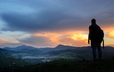 Obraz premium A traveler-photographer observes the sunset over the forest and mountains in the Ukrainian Carpathians