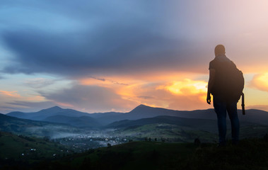 A traveler-photographer observes the sunset over the forest and mountains in the Ukrainian Carpathians