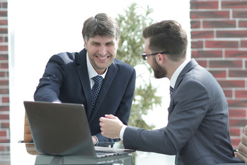 Two businessmen working together using laptop on business meeting in office