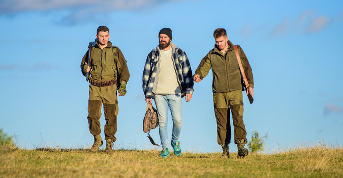 Brutal hobby. Guys gathered for hunting. Group men hunters or gamekeepers nature background blue sky. Men carry hunting rifles. Hunting as hobby and leisure. Hunters with guns walk sunny fall day