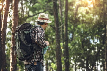 Obraz premium Hiker man with backpack is walking in forest