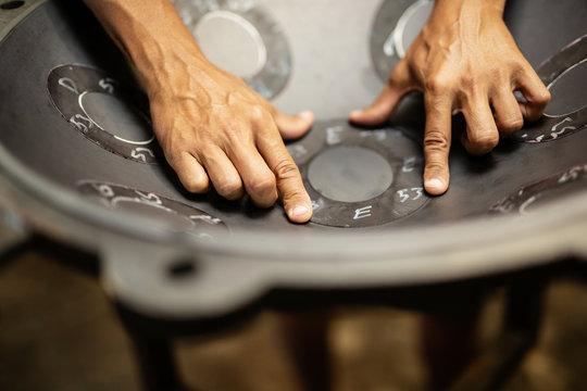 Hands designing handpan in a workshop