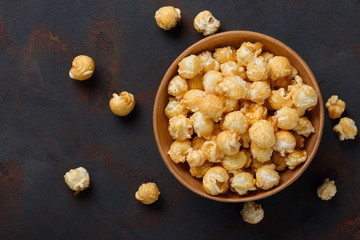 Caramel popcorn in bowl on dark table background top view