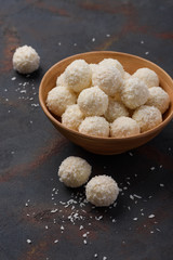 Coconut candies bowl on dark rustic table background