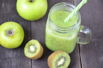 Green healthy smoothie in glass jar: banana, kiwi, green apple on rustic background