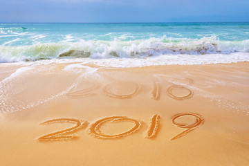 Fototapeta na wymiar 2019 written on the sand of a beach, travel 2019 new year concept
