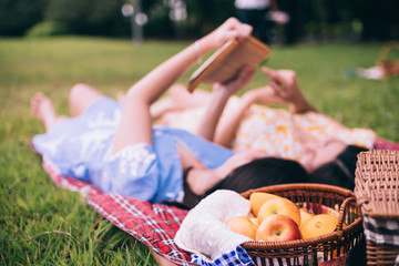Two female friends enjoying picnic together in a park. Selective focus