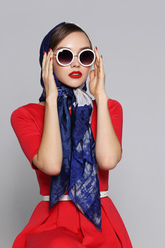 Young woman in retro style. Sunglasses and silk scarf.