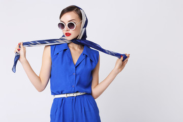 Young woman in retro style. Sunglasses and silk scarf, blue overalls.