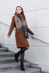 Fashion young woman outdoor. Wearing coat, scarf, and handbag