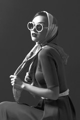 Young woman in retro style. Sunglasses and silk scarf.