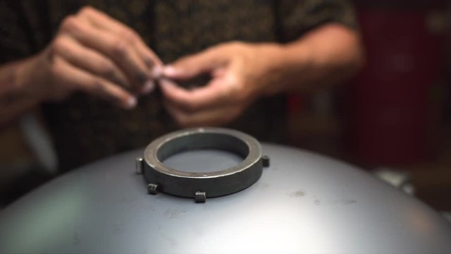 Artisan hands designing Handpan in his workshop, a metal percussion instrument.