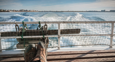 relaxed man sitting at the back of a ferry leaving the port towards Yeu Island