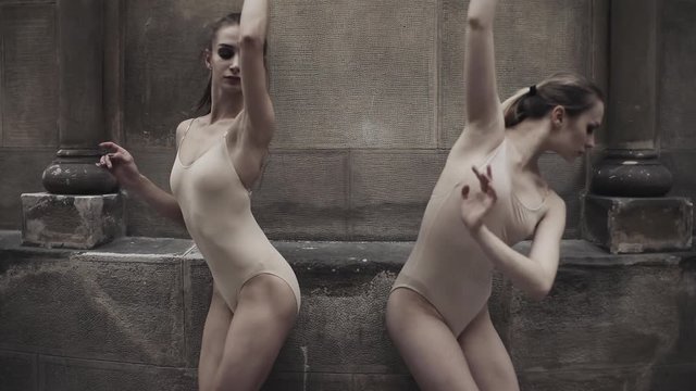 Young professional female dancers is performing acrobatic dance along the medieval street