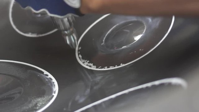 Artisan in his workshop using air hammer to construct a handpan, metal percussion instrument.