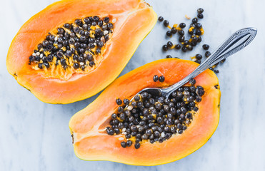Fresh papaya fruit with seeds on white marble table top view.