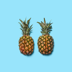 Pineapple with green leaves cut into pieces presented on a blue background with space for text. Creative layout for your ideas. Flat lay