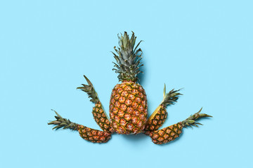 Food composition of a whole and pieces of pineapple on a blue ba