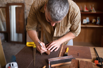 Close view of a wood carpenter using the chisel. A craftsman at his table, carving from the wood.