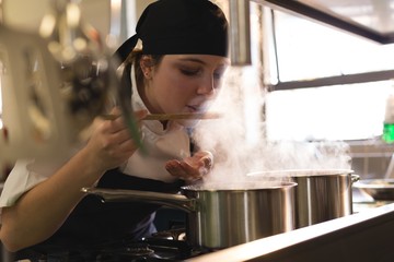 Female chef tasting food in kitchen