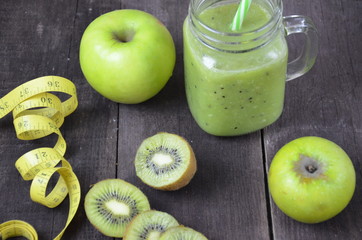 Green healthy smoothie in glass jar: banana, kiwi, green apple on rustic background