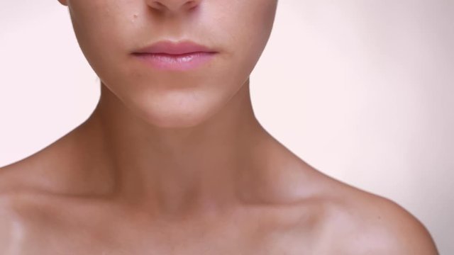 Focused face, chin and collarbone of caucasian woman with pure smooth skin in light studio nude