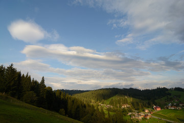 Landscape area (village houses, firs, pines, trees, mountains, hills, sunset). Nature and man. Natural background.