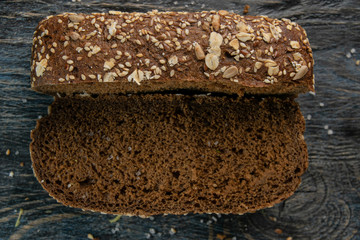 photo of black bread with a knife on a black wooden background.