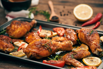 Grilled chicken drumstick and wings on baking tray over wooden table