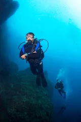 Gordijnen Scuba divers underwater in the deep blue ocean and backlight sun. © frantisek hojdysz