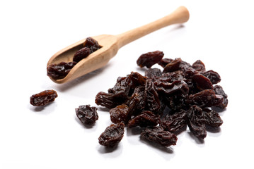 Close-up of jumbo-sized raisins in a wooden soon on white background