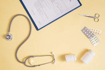 Doctor's stethoscope with patient form and bottle of pills on the desk