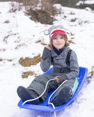 Fototapeta na wymiar portrait of a boy sitting in a toboggan waiting to go sledding