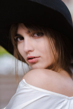 Closeup portrait of attractive young woman wearing black hat posing at the city