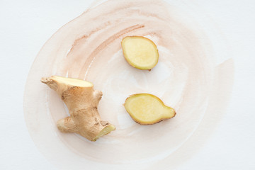 top view of sliced ginger root on white surface with watercolor strokes