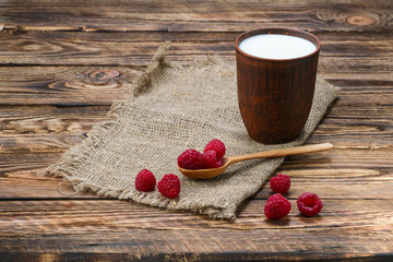 Cottage cheese and milk in clayware on wooden table, sackcloth table-napkin and wooden spoon
