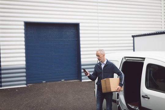 Delivery man using mobile phone at warehouse