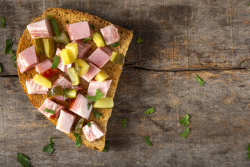Open sandwich with pieces of smoked bacon, pickles and chopped parsley